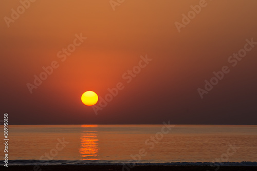 Fototapeta Naklejka Na Ścianę i Meble -  warm orange sun at the horizon from the sea and waves