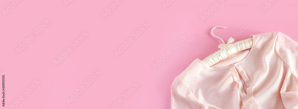 Pink woman blouse is hanging on beautiful hanger on pink background with copy space. Sale and shopping concept. Banner Pink woman blouse is hanging on beautiful hanger on pink background with copy space. Sale and shopping concept. Banner