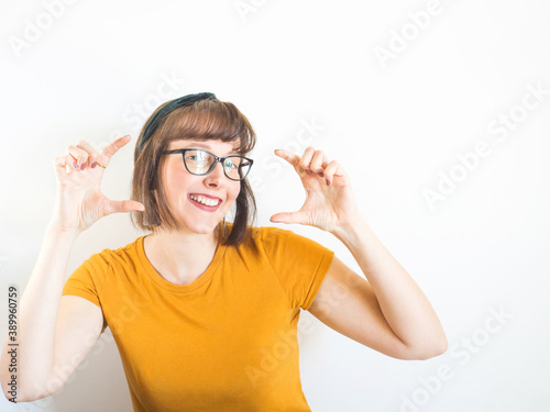 Cute and confident smiling girl wearing eye glasses with perfect white teeth after orthodontic treatment making gesture with hands