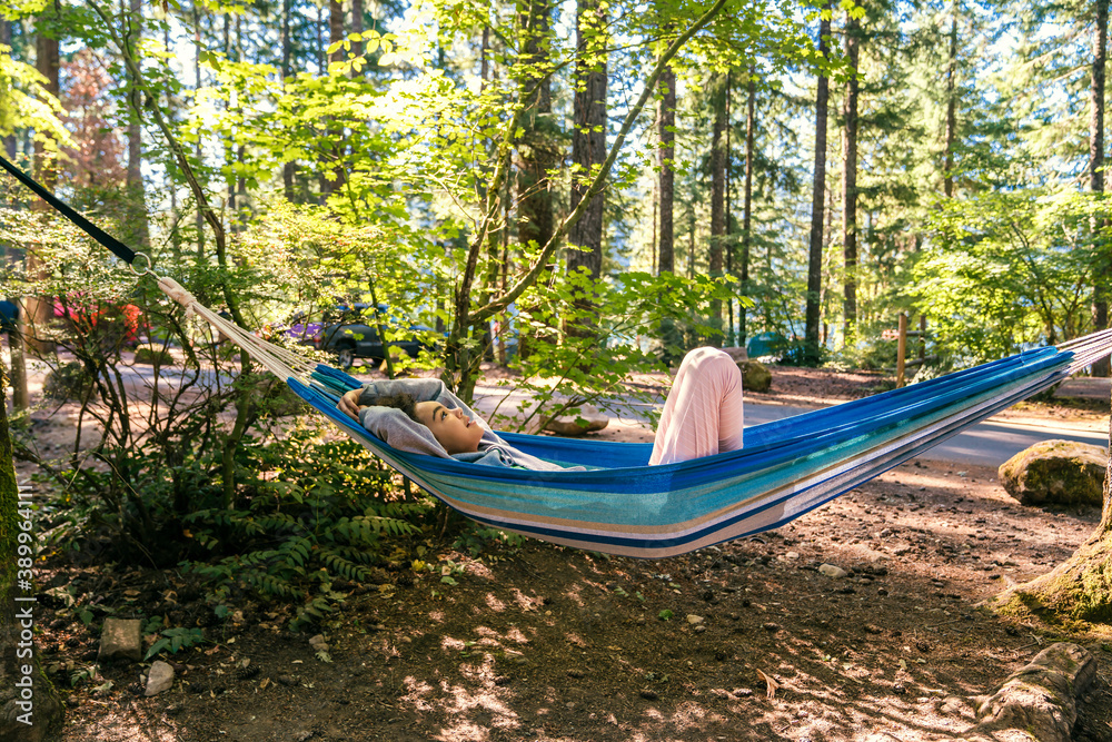 Happy, smiling girl relaxing in hammock in forest campground Happy, smiling girl relaxing in hammock in forest campground
