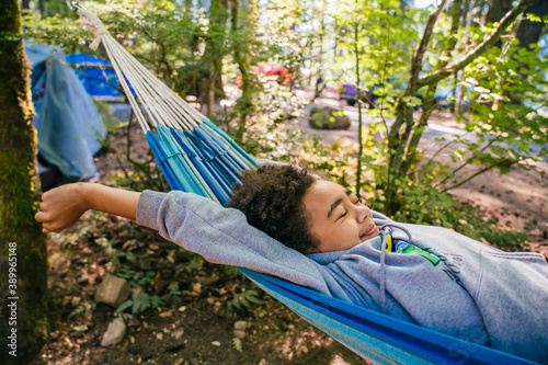 Teen girl stretching in hammock in forest 