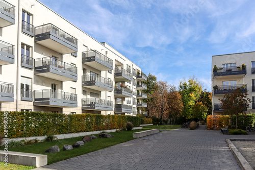 Cityscape with modern residential area, new apartment buildings and green courtyard with pedestrian walkway and trees in autumn