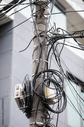 Many unorganised internet and TV cables on a concrete pole in Bucharest.
