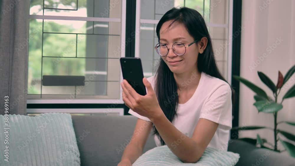 Asian woman using smartphone in living room.