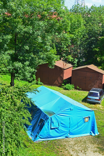 Two metal garages, car and a plastic tent in the yard