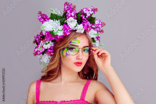 Woman with floral lilac flowers headband holding round retro eyeglasses