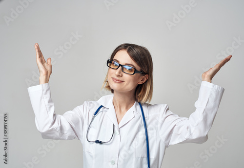 female nurse in a medical gown gesturing with her hands on a light background
