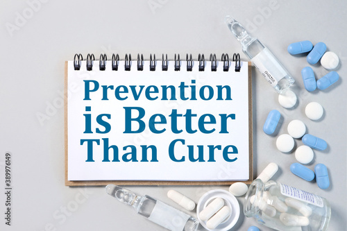 Fotografie prevention is better than cure, text on white paper on gray background near medication