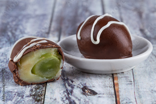 Chocolate truffle with green grape filling isolated on white background. Closeup photography. photo