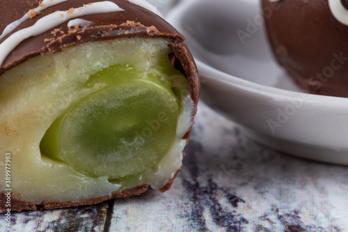 Chocolate truffle with green grape filling isolated on white background. Closeup photography. photo