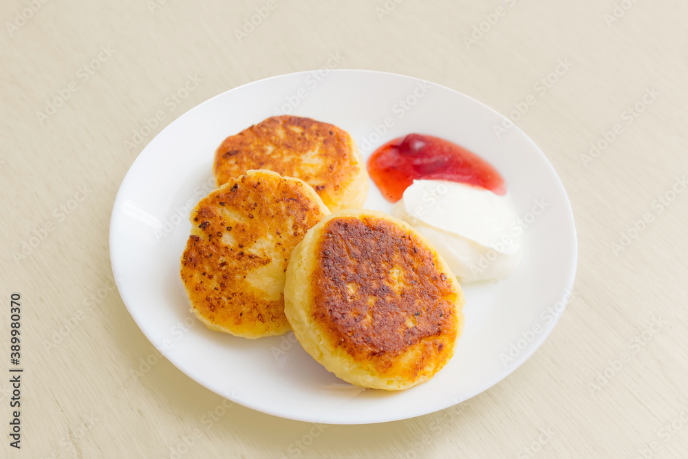 three cheese pancake on a plate with sour cream and jam, cottage cheese three cheese pancake on a plate with sour cream and jam, cottage cheese