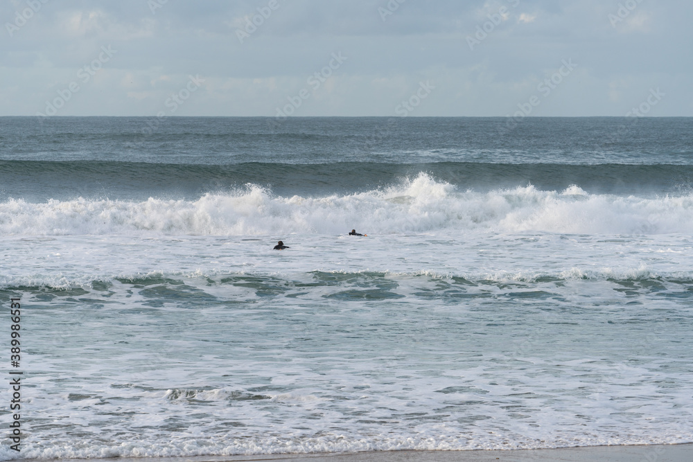 Surfers surfing in Baleal Island beach atlantic ocean waves in Peniche, Portugal