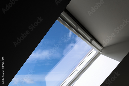 Interior view and close-up detail at closed white Tilt Window Skylights at attic and background of sunny blue sky.