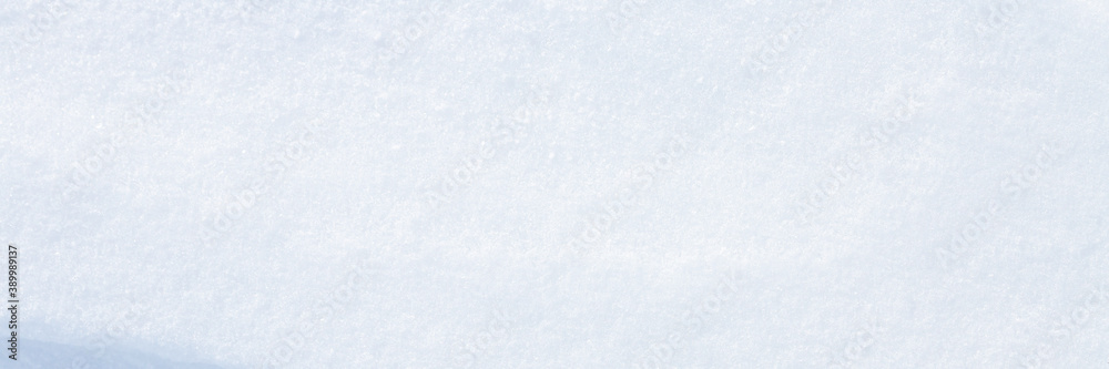 Beautiful winter background with snowy ground. Natural snow texture. Wind sculpted patterns on snow surface. Wide panoramic texture for background and design. Closeup top view with copy space.