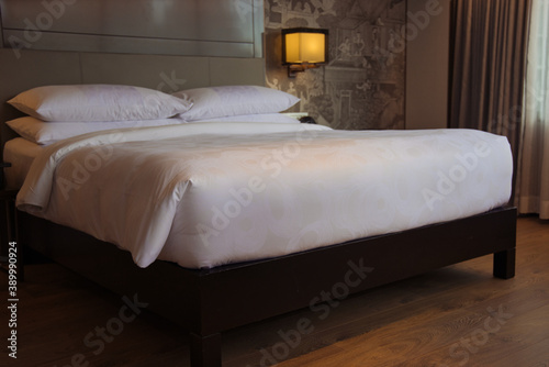 This unique photo shows a large bed standing in a hotel room. with bedside tables and beautiful lamps