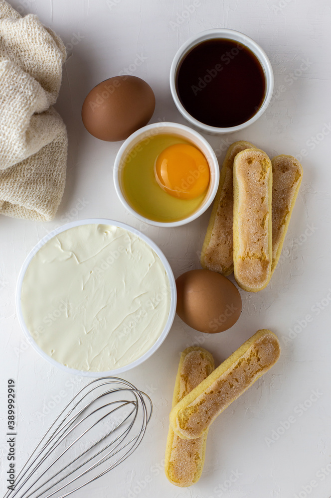 Ingredients for tiramisu, preparing tiramisu. Eggs, ladies finger cookies, mascarpone, coffee, whisk for beating eggs on a white background.