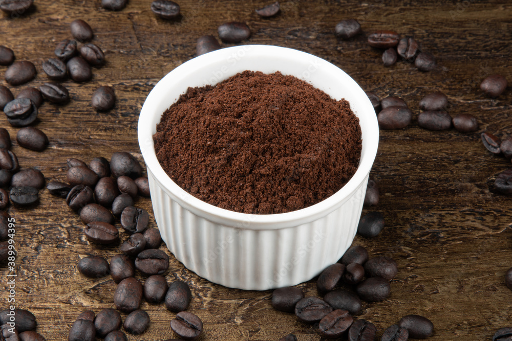 Roasted coffee beans in powder in white bowl. Rustic background. Roasted coffee beans in powder in white bowl. Rustic background.