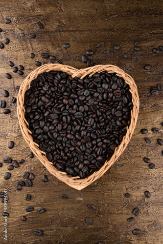 Roasted coffee beans in heart shaped basket. Top view.