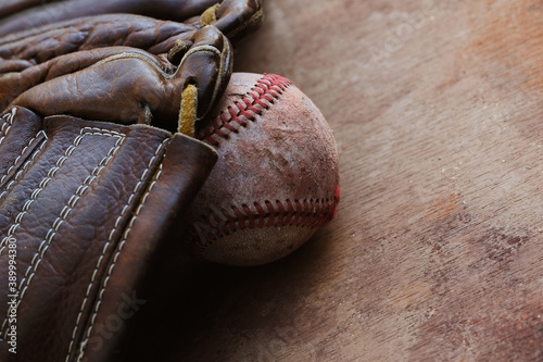 Vintage baseball glove and ball close up on brown texture background.