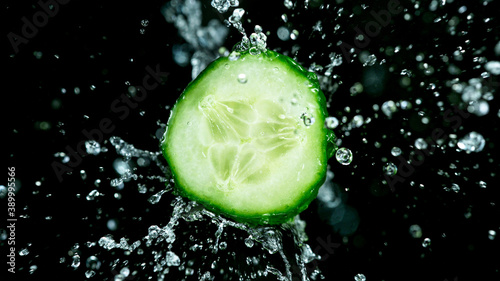 Freeze motion of flying cucumber in the air with water splashes, isolated on black background