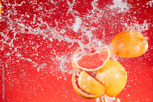 Fototapeta Naklejka Na Ścianę i Meble -  Fresh Grapefruit Slices with Water Splash Isolated on Red Background.