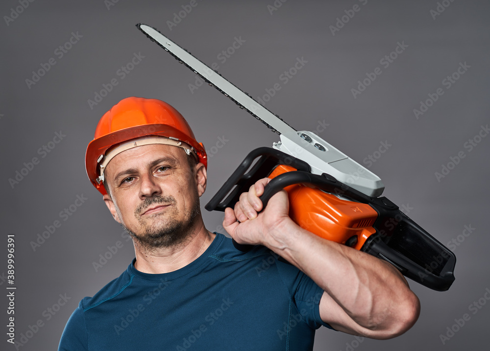 Worker in hardhat with chainsaw