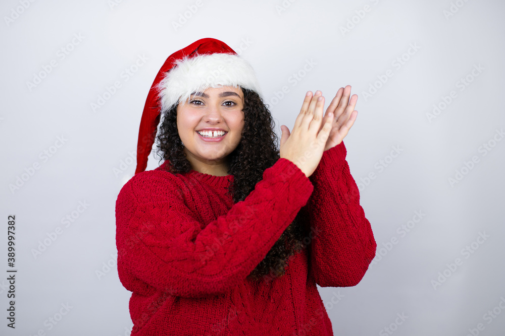 Young beautiful woman wearing a Santa hat over white background clapping and applauding happy and joyful, smiling proud hands together