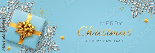 Christmas banner. Realistic blue gift box with golden bow, silver shining snowflake, gold stars and glitter confetti. Xmas background, horizontal poster, greeting cards, headers website. Vector.