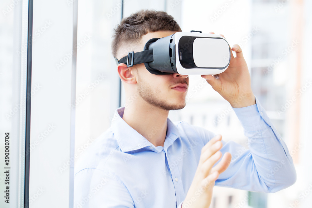 Young man wearing virtual reality glasses in modern office. Young man wearing virtual reality glasses in modern office.
