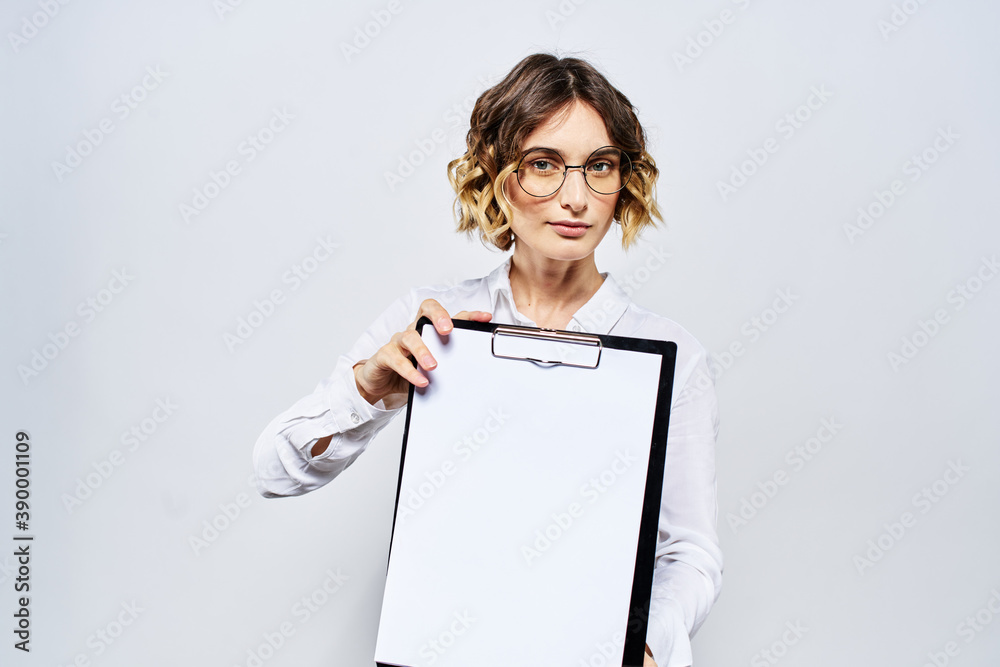 Business woman with a folder of white documents in her hand on a light background And hairstyle glasses model Business woman with a folder of white documents in her hand on a light background And hairstyle glasses model
