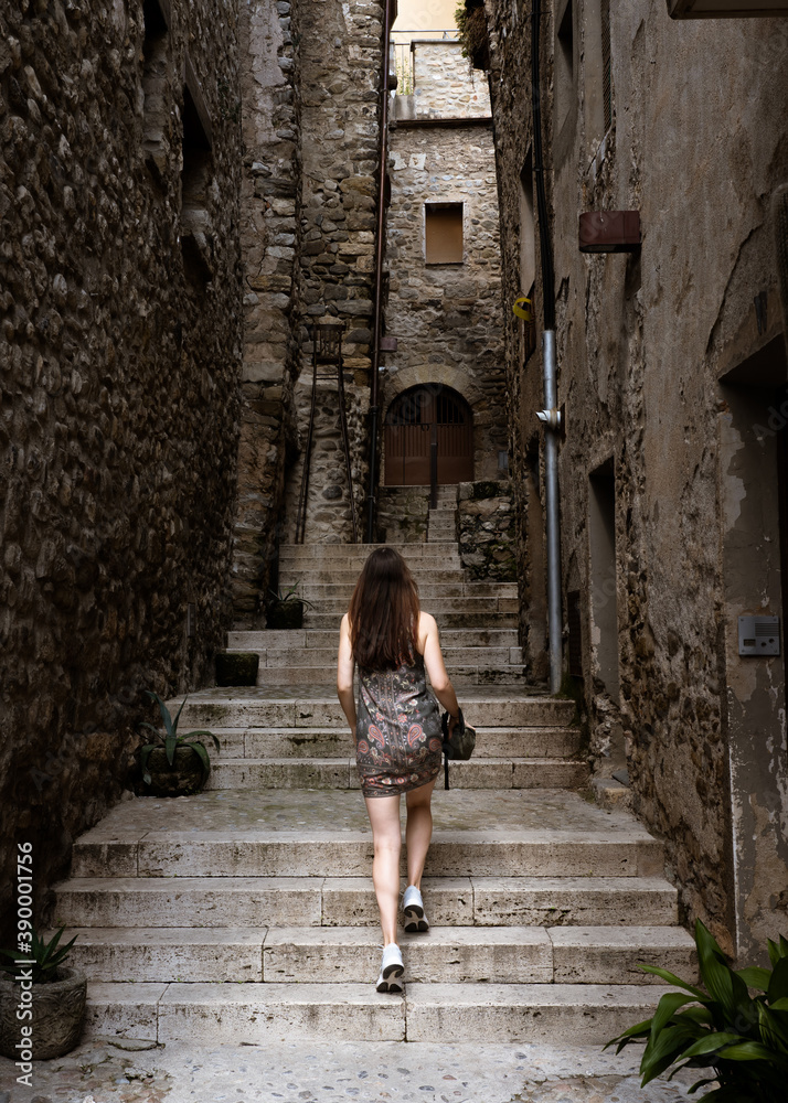 Young woman walking up a stairway in medieval town Besalú, Spain