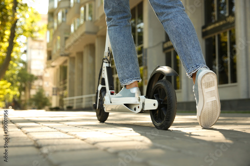Woman riding electric kick scooter outdoors, closeup. Space for text photo