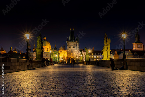 old paved sidewalk with paving stones in memory of Charles Bridge from the 14th century in the center of Prague and in the background the old bridge tower at night in the Czech Republic