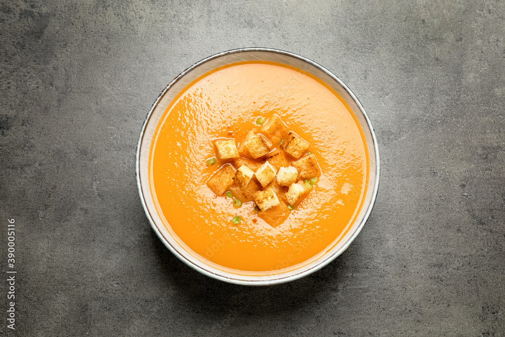 Tasty creamy pumpkin soup with croutons in bowl on grey table, top view