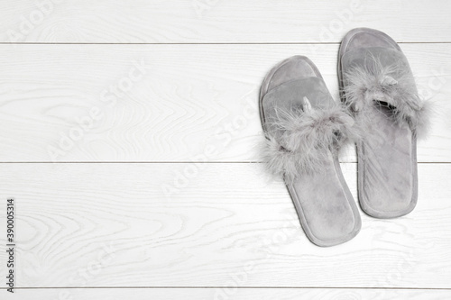 Pair of soft slippers on white wooden background, flat lay. Space for text