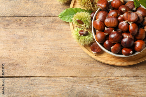 Fresh sweet edible chestnuts on wooden table, top view. Space for text
