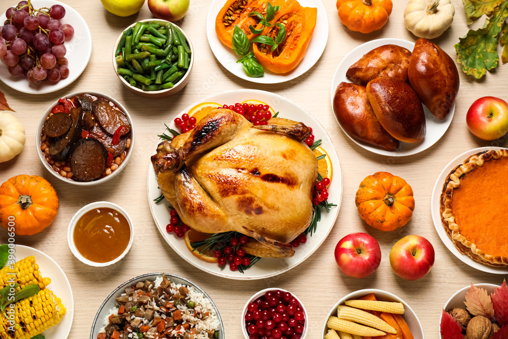 Traditional Thanksgiving day feast with delicious cooked turkey and other seasonal dishes served on wooden table, flat lay Traditional Thanksgiving day feast with delicious cooked turkey and other seasonal dishes served on wooden table, flat lay