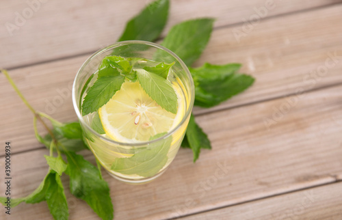 A glass of lemon mint water and fresh mint leaves