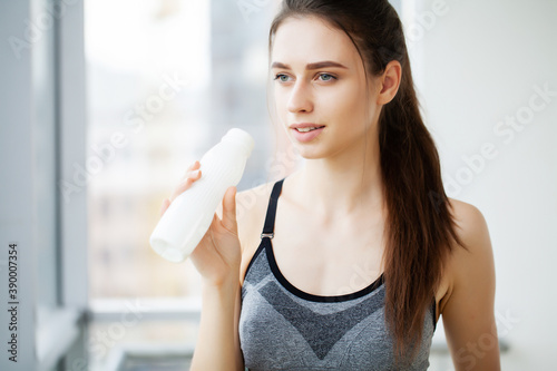Young beautiful woman drinking from plastic bottle of yogurt