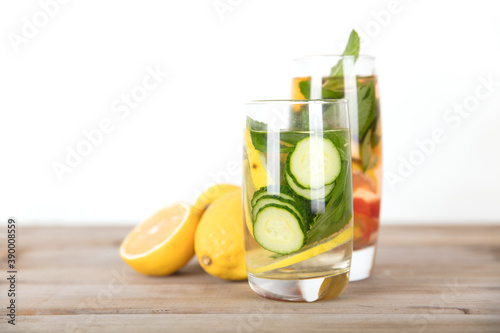 Two glasses of lemon slices, cucumber slices and mint leaves infused beauty water and fresh lemon fruit on the table