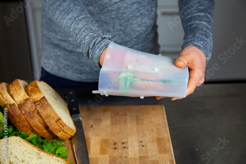 A women prepares lunch and puts a sandwich into a food-grade silicone bag as part of a zero-waste lifestyle to replace plastic bags photo