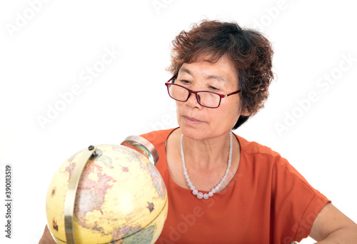 Фотография An elderly female with an Asian face in glasses is observing on the globe with a