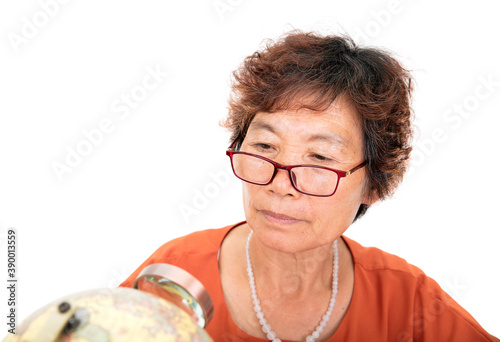 Konstfotografi An elderly female with an Asian face in glasses is observing on the globe with a