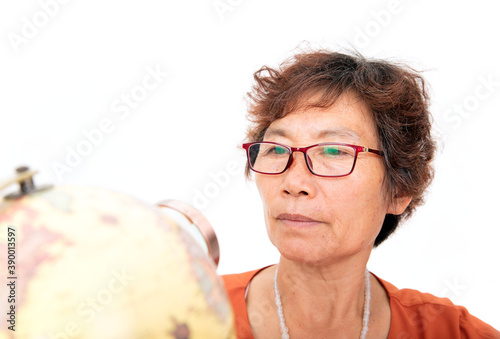 Фотография An elderly female with an Asian face in glasses is observing on the globe with a
