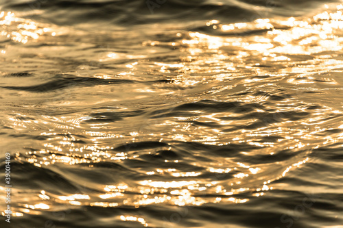 Water surface with moving wave of golden water reflecting .
