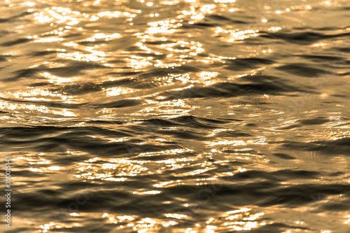 Water surface with moving wave of golden water reflecting .