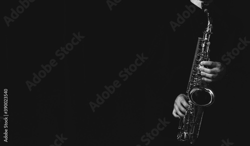 Canvas Print Grayscale shot of a cool and handsome guy playing his saxophone isolated on a da