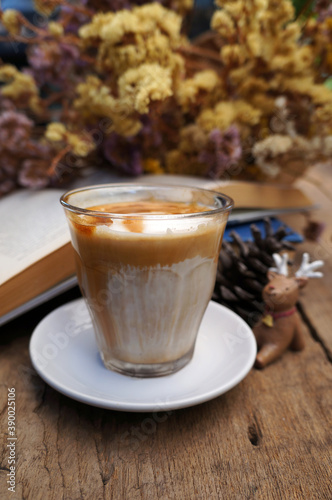 Dirty coffee or milk coffee, top with coffee shot on a wooden table, flower background.