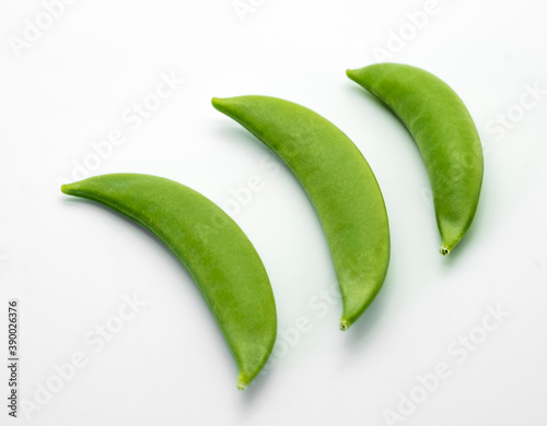 Three green peas on a white background to be used as part of any graphic design or advertisement.