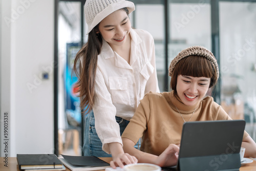 Two young asian woman talking and working together at office.